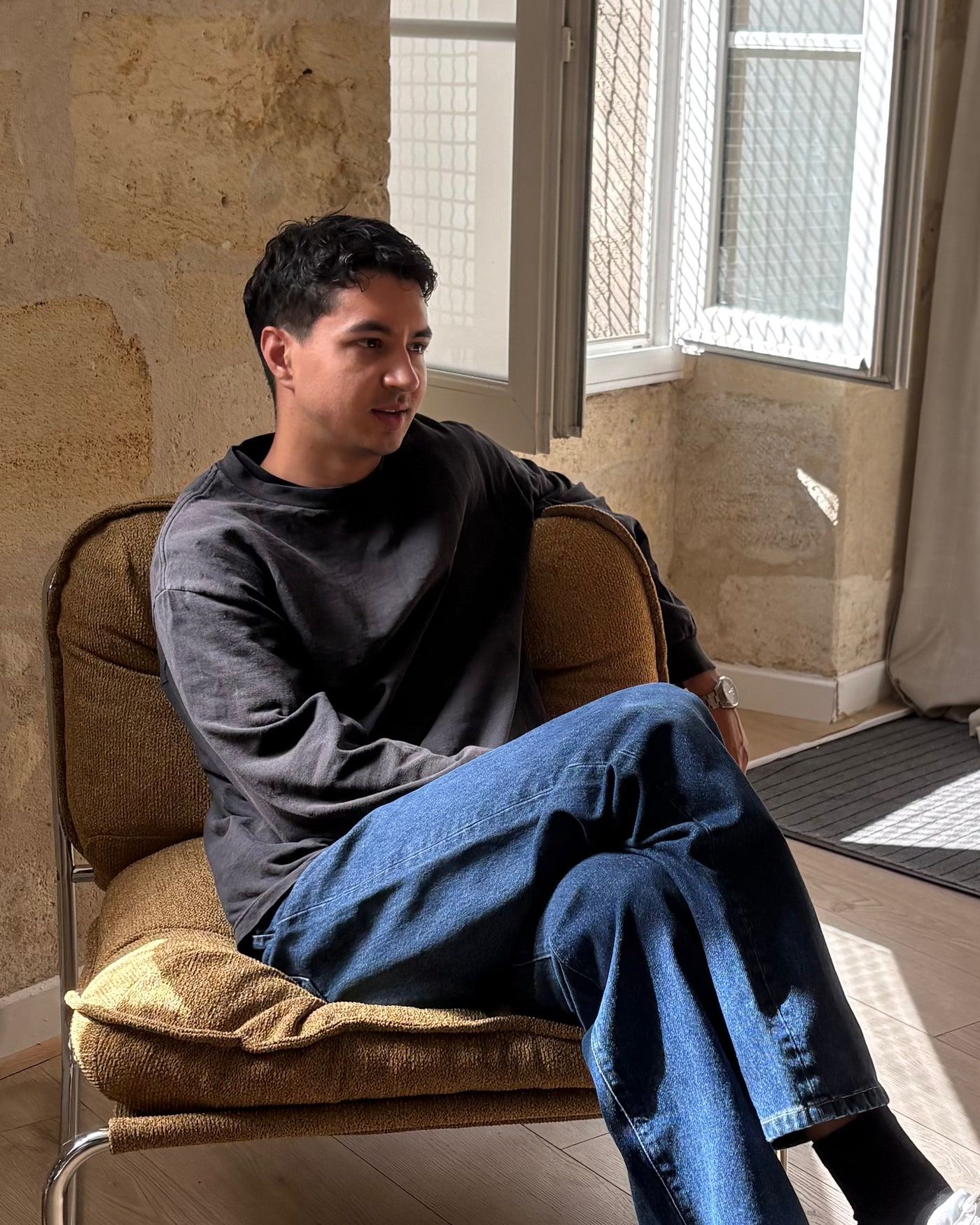 Portrait de Thomas Bourhis, en t-shirt sombre, regard tourné vers la fenêtre.